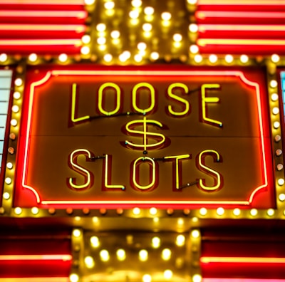 Bright neon lights display the words 'Loose Slots' with a dollar sign in the center. The sign is outlined with bulbs, creating a vibrant and flashy effect typical of a casino or entertainment venue.